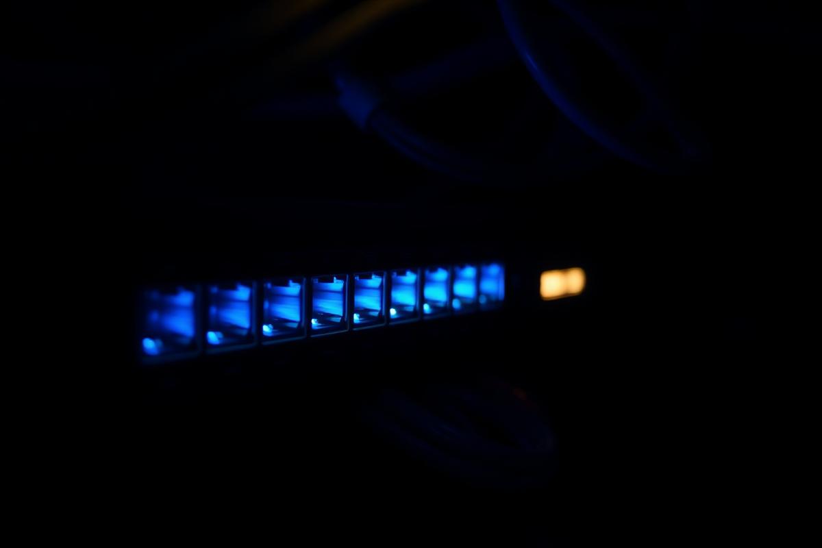 Network switch with glowing blue ethernet ports in a dark equipment room